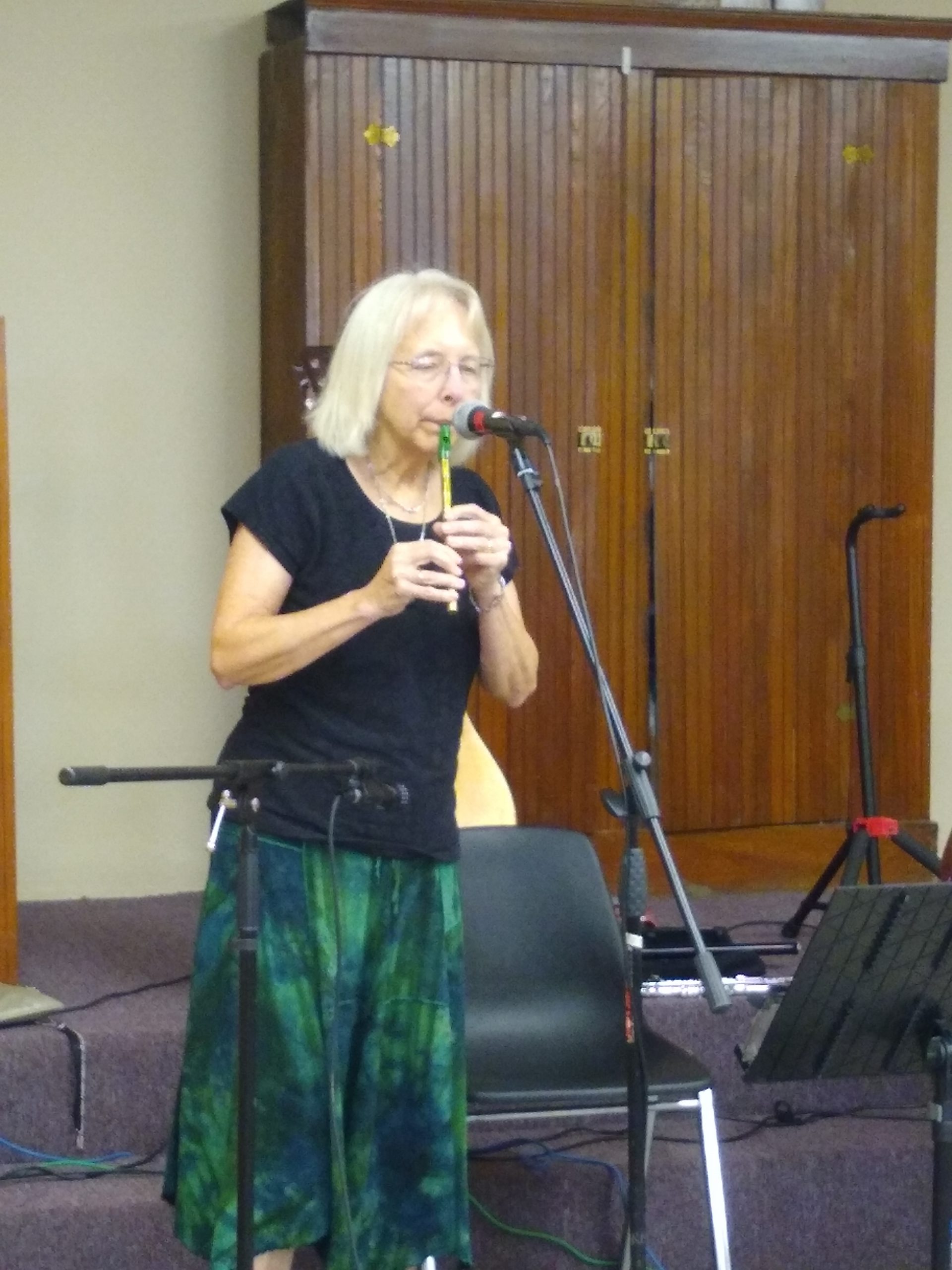 A woman plays a tin whistle